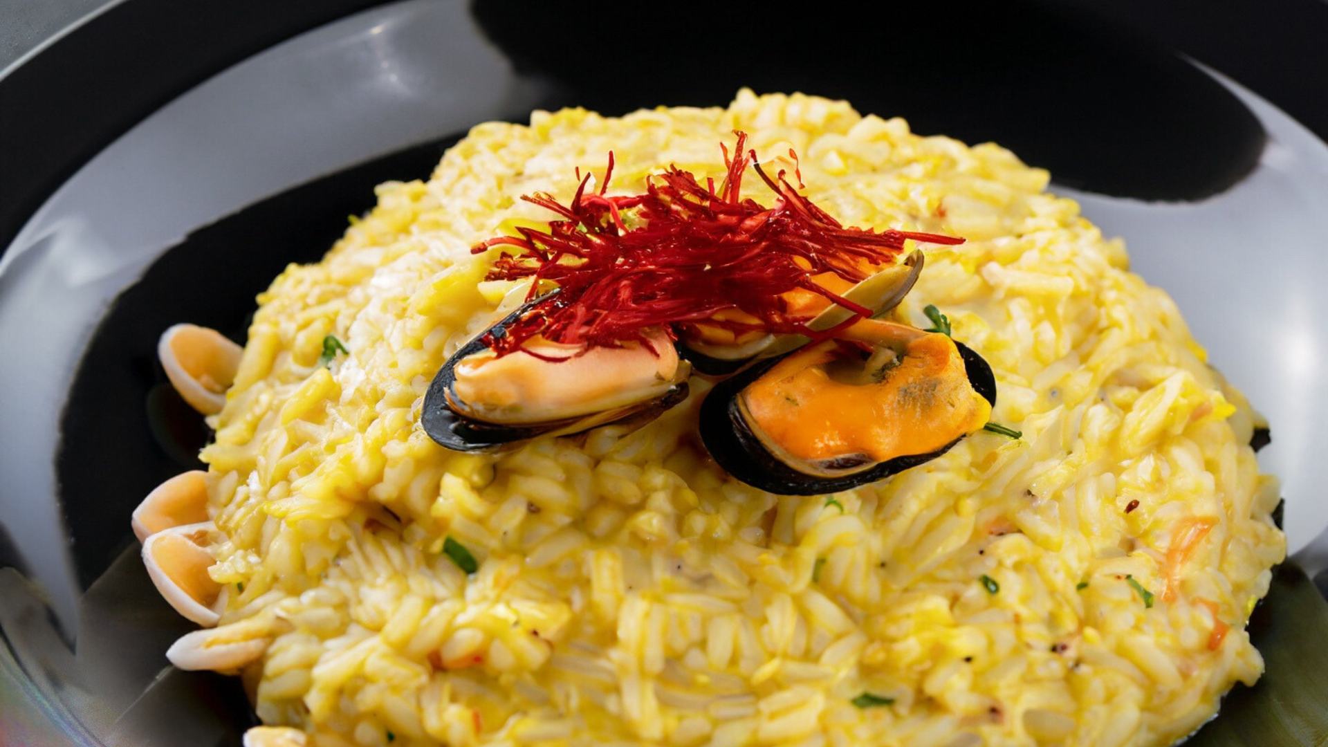 Risotto zafferano e pesce guarnito con stimmi di zafferano e cozze